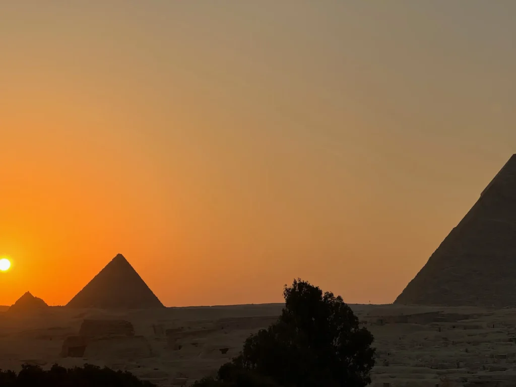 Il sole che cala dietro le piramidi, da una terrazza di Giza. Ottobre 2023.