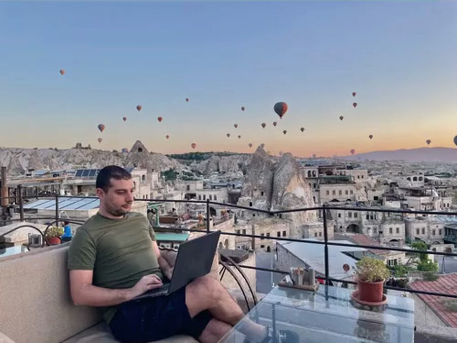 Christian Cannata al portatile su una terrazza in Cappadocia, con le mongolfiere in cielo