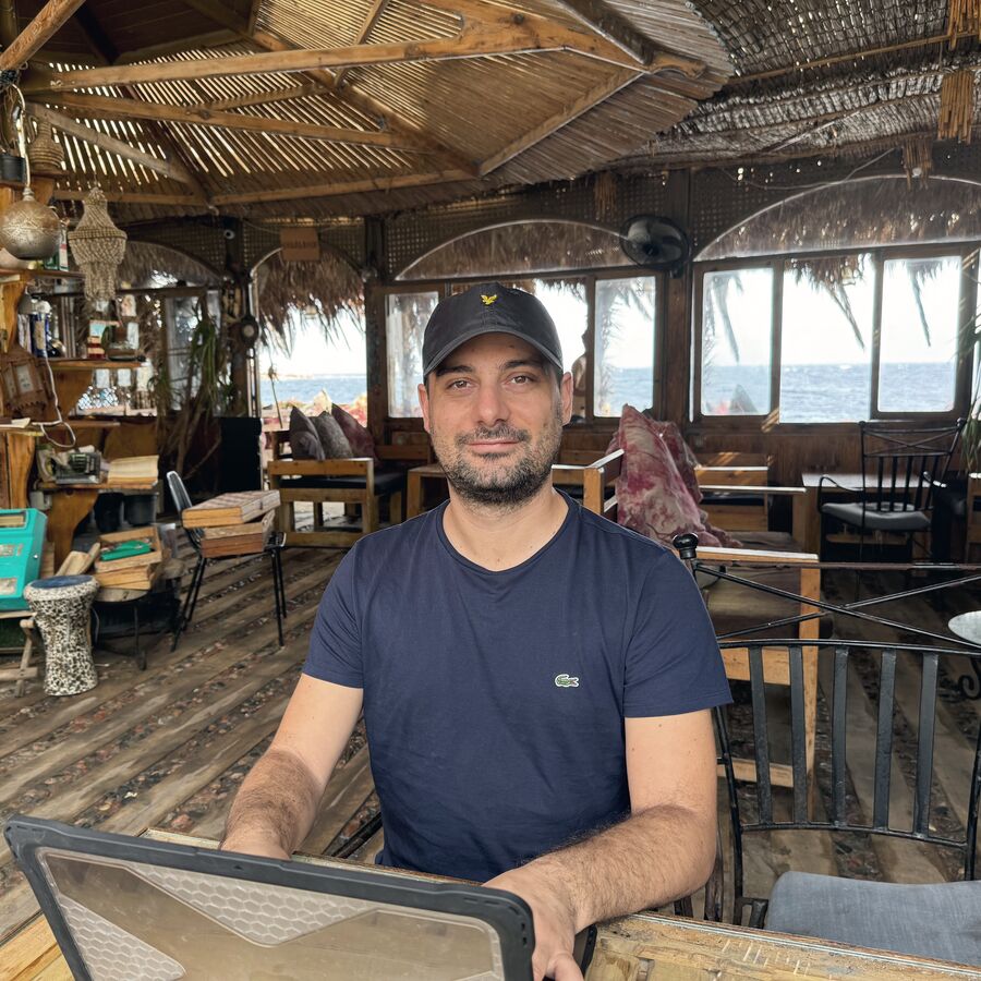 Christian Cannata al portatile in un caffè di legno sul mare a Dahab